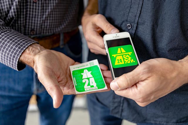 Die Klebevignette 2024 (links) ist autobahngrün. Die parallel erhältliche E-Vignette (rechts) gibt es nur virtuell. Hinweis: Das E-Vignetten-Icon auf dem Handy ist ein Symbolbild; es gilt nicht als echte Vignette. Foto: BAZG